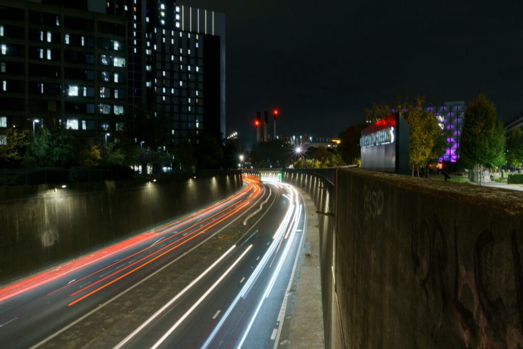 Dynamic night cityscape in Leeds featuring vibrant car light trails and modern architecture.